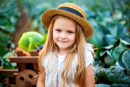 Time to harvest. Portrait of a happy blonde girl in straw hat on cabbage fieldの写真素材