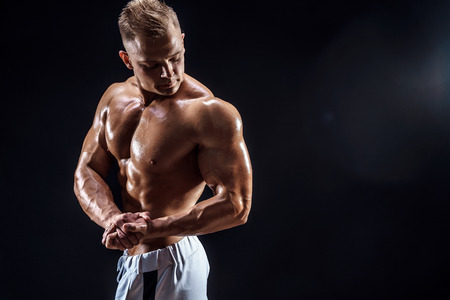 Handsome strong bodybuilder posing in studio on black backgroundの写真素材