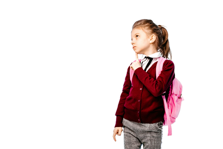 Back to school. Beautiful little girl dressed like a School girl - in white shirt, red blouse and gray pants hold a school bag and posing like model. Isolated on white.の写真素材