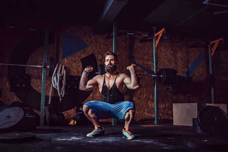 Muscular fitness man preparing to deadlift a barbell over his head in modern fitness center....