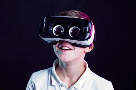 Side view of excited kid in white t-shirt and virtual reality headset standing bending forward...