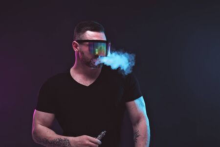Men with beard in sunglasses vaping and releases a cloud of vapor.
