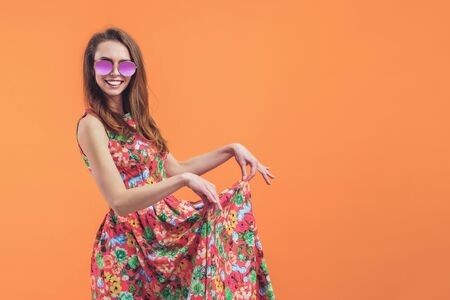 Girl in floral dress emotionally poses on the orange background.の写真素材