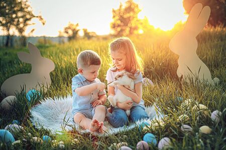 Little girl and boy play with the rabbit. happy little girl holding cute fluffy Bunny. Friendship...