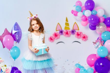 Unicorn Girl holding gift box. Idea for decorating unicorn style birthday party. Unicorn decoration for festival party girl.の写真素材