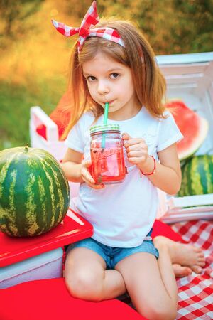 Child drinking Watermelon lemonade in jar with ice and mint as summer refreshing drink. Cold soft drinks with fruit.の写真素材