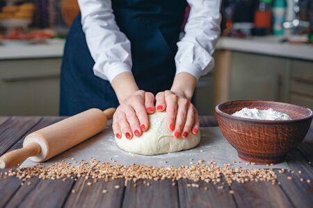 Faceless shot of woman in white shirt and apron flour dough while cooking.