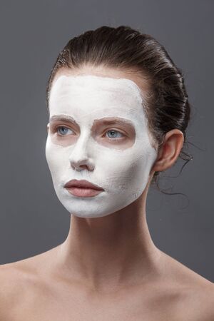 Beautiful girl is applied a white cosmetic mask from black dots. Isolate, studio.の写真素材