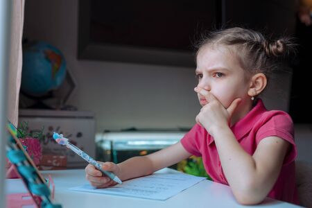little girl at distance home schooling, study lessons on quarantine.