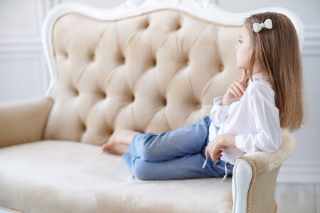 Little cute girl lies on the sofa in the room.の写真素材