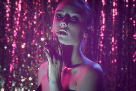 Beauty portrait of a High Fashion model woman in colorful bright neon lights posing in studio, night...