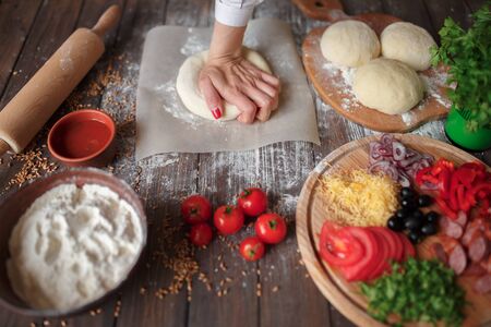 woman kneads the dough with hands while cooking pizza