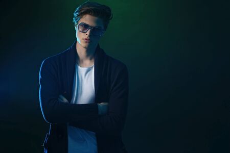 Trendy young man with cool hairstyle wearing black jacket with sunglasses. High Fashion male model...