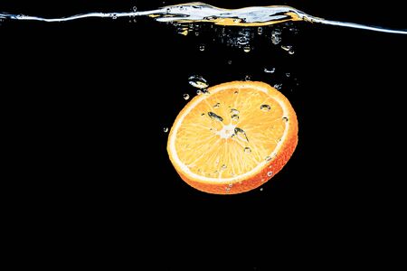 orange in water on a black background under water with bubbles.の写真素材