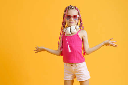 Crazy expressive trendy DJ girl in bright clothes, headphones and bright dreadlocks. Disco, party. Bright fashion.の写真素材