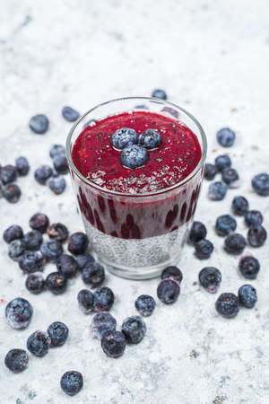 Healthy breakfast or morning snack with chia seeds and blueberries on white stone background, vegetarian food, diet and health concept.の写真素材