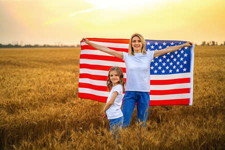 Mother and daughter with American Flag in a beautiful wheat fieldの写真素材