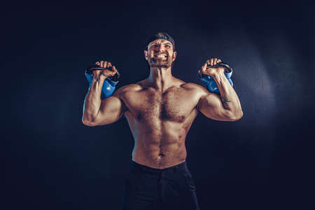 Aggressive bearded muscular bodybuilder doing Exercise for the shoulder muscles, deltoid with...