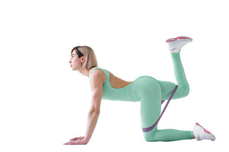 Sexy woman in sportswear using a resistance band in her exercise routine. Young woman performs...