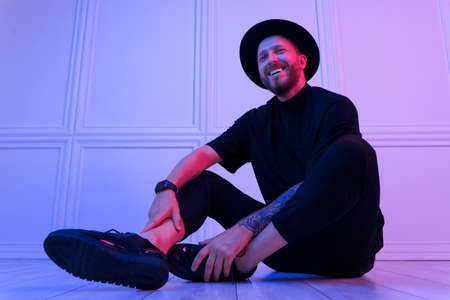Fashionable guy. Studio shot in dark studio with neon light. Portrait of serious man.の写真素材