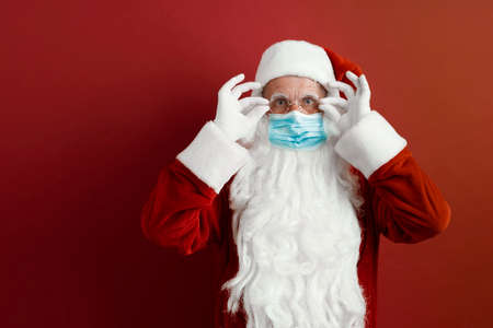 Santa Claus in a medical mask on a red background.の写真素材