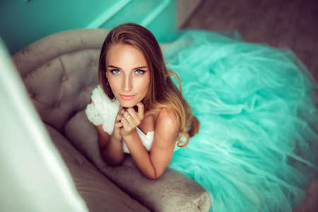 Young woman in green dress posing on sofa.の写真素材