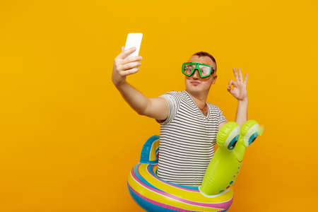 Man wearing underwater mask, striped shirt, swimming laps looking into the phone, taking very...