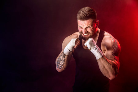 Sportsman muay thai boxer fighting on black background with smoke. Sport concept.