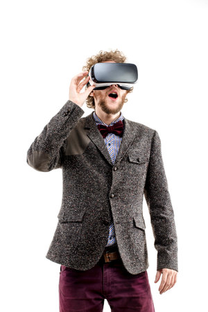Young curly-haired businessman wearing brown suit use a VR headset and experiencing virtual reality...