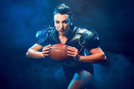 Young brunette wearing sexy uniform of rugby football player posing with ball.の写真素材