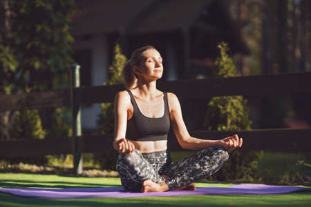 Woman practicing morning yoga at backyard. Healthy lifestyle.の写真素材