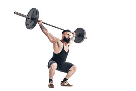 The technique of doing an exercise of deadlift with a barbell of a muscular strong tattooed bearded sports men on a white studio background. Isolate.の写真素材