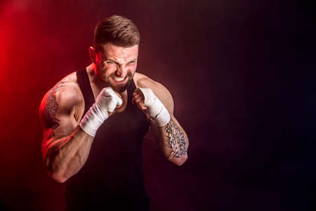Sportsman muay thai boxer fighting on black background with smoke. Sport concept.
