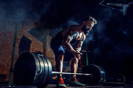 Muscular fitness man preparing to deadlift a barbell in modern fitness center. Functional training. Snatch exerciseの写真素材