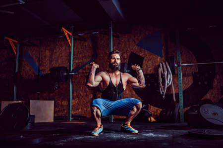 Muscular fitness man preparing to deadlift a barbell over his head in modern fitness center. Functional training. Snatch exerciseの写真素材