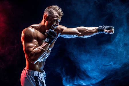 Studio portrait of fighting muscular man in smoke on dark backgroundの写真素材