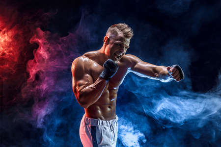 Studio portrait of fighting muscular man in smoke on dark backgroundの写真素材