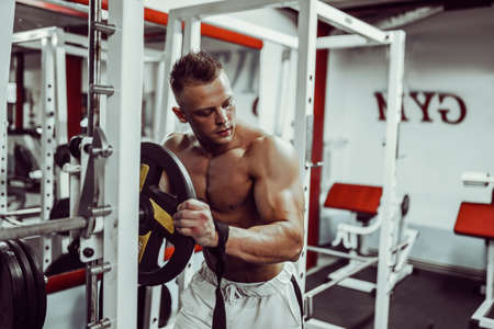 Bodybuilder preparing for heavyweight exercise with barbell in gym