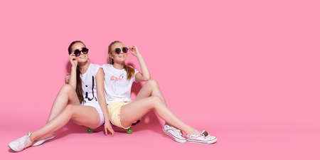 Two girl skaters go crazy and have fun together. Beautiful sporty women, positive emotion. Pink...