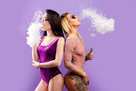 Two women in bodysuits vaping in studioの写真素材