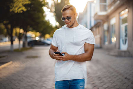 Young Man with mobile phone walking, background is blured city