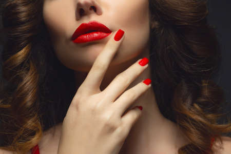 Beautiful girl showing red manicure nails . makeup and cosmetics. Brunette girl with long and shiny curly hairの写真素材