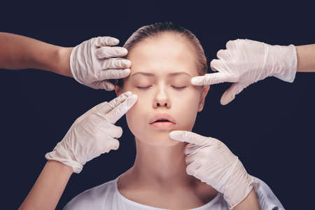 Young woman with eyes closed having an medical exam of her face skin by plastic doctorsの写真素材