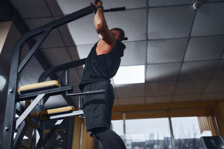 Man in gym doing exercises on crossbar in gym