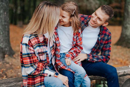 photo of a wonderful family in the autumn forest on a benchの写真素材