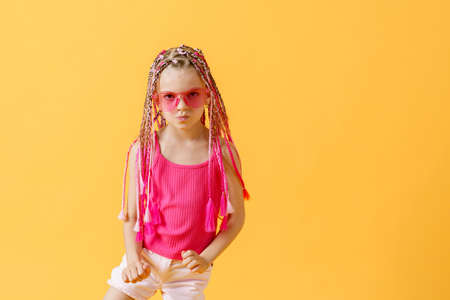 Stylish girl with pink dreadlocks and posing on a yellow backgroundの写真素材