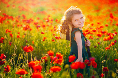 beautiful girl in poppy field enjoys the beauty and aromas.の写真素材