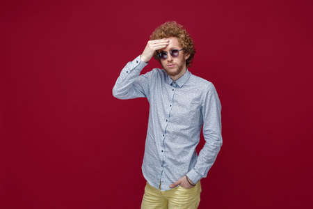 Portrait of elegant young man in sunglasses on red backgroundの写真素材