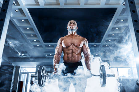 Muscular man working out in gym doing exercises with dumbbells at biceps, strong male naked torso absの写真素材