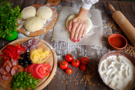 woman kneads the dough with hands while cookingの写真素材